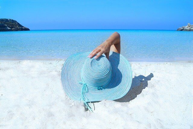 帽子をかぶった女性が浜辺で寝ている