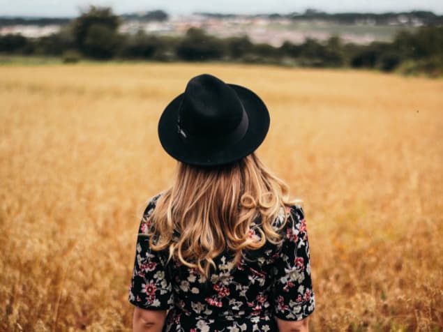 帽子を被った畑を見る女性