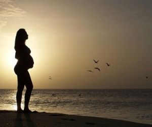 夕方の浜辺に立つ妊婦