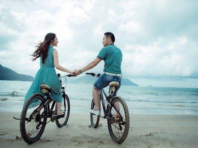 海辺で自転車に乗るカップル