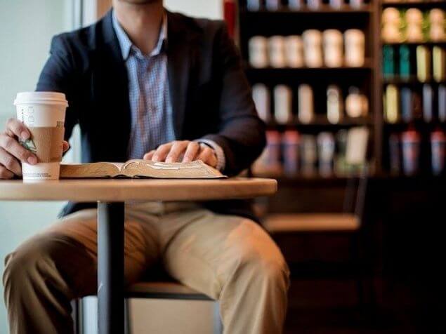喫茶店のテーブルの椅子に座る男性