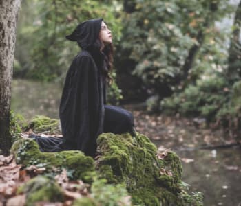 森の中で大きな石に座り、ぼんやりしている女性。
