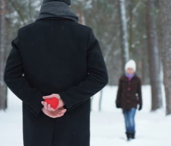 雪の中で女性にハートマークを渡そうとする男性。