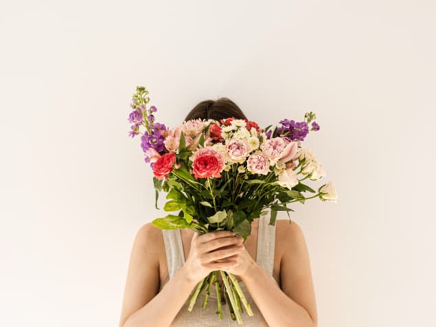シンプルな部屋、花束で顔を隠した女性