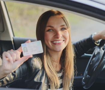女性が笑顔で運転免許証を持っている
